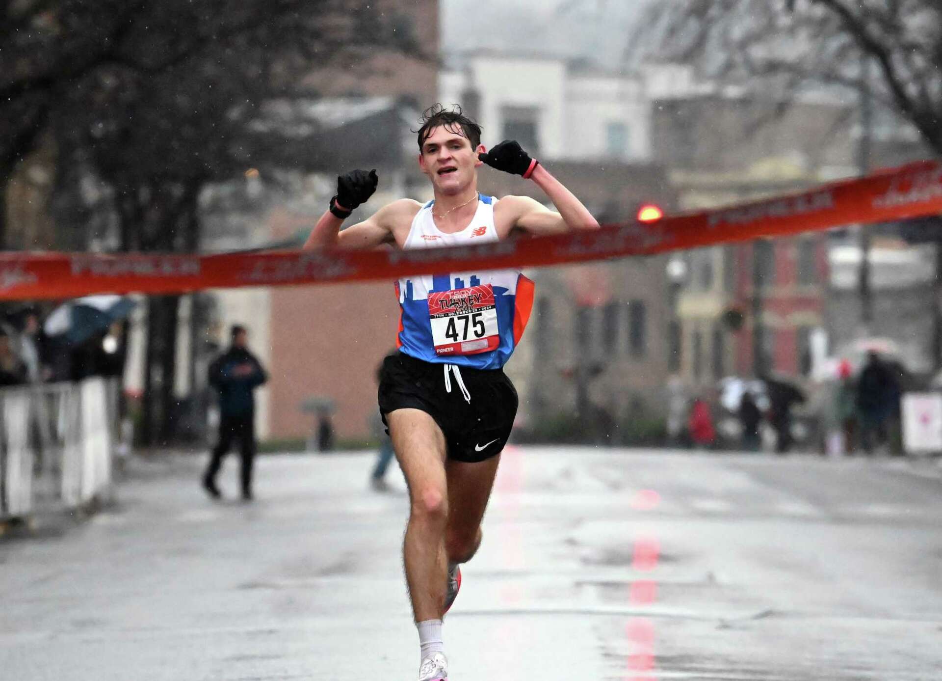A runner crossing the finish line in the rain